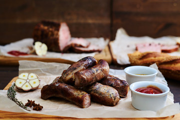 Grilled sausages with sauces lying on the wooden board