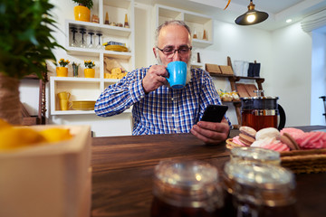 Happy smiling mature man enjoying a cup of tea while holding a t