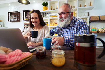 Low angle of smiling couple sitting in front of netbook and look
