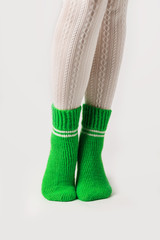 Female legs in white stockings and green knitted socks.
