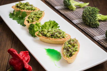 Tartlets stuffed with minced meat  broccoli and tuna. Wooden background