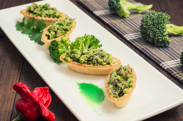 Tartlets stuffed with minced meat  broccoli and tuna. Wooden background