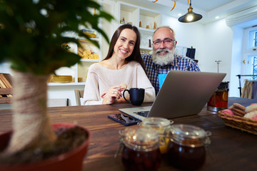 Senior man sitting near affectionate woman looking at the camera