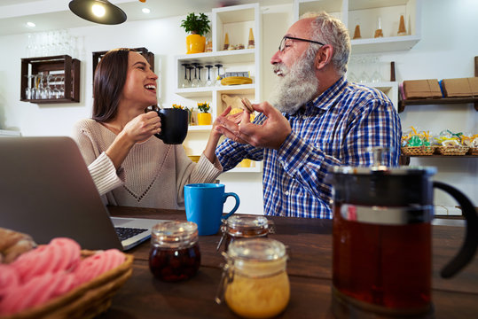 Two people laughing and looking at each other when eating macaro