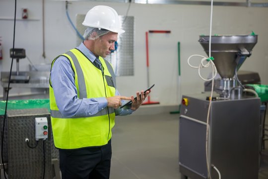 Technician using digital tablet at meat factory