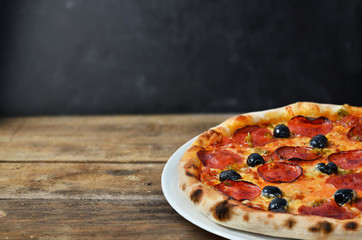 Hot Pepperoni Pizza with olives on old wooden planks