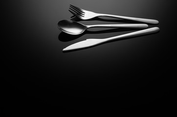 Black food background. Stainless steel, modern silverware on black background with reflection. Image with copy space. Symbol or concept for diners, cafes and good food competitions and festivals