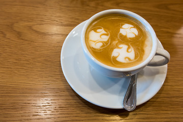 A cup of Latte art on wooden bar