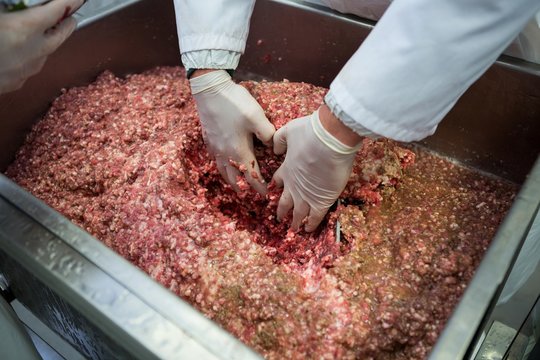 Hands of butcher mixing minced meat