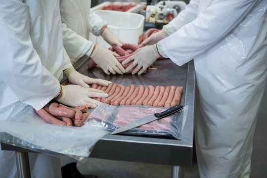 Butchers packing raw sausages