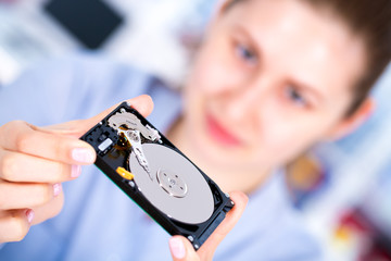 Smiling girl with hard driver. Young woman technician with open HDD in hand