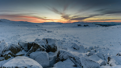 Amazing winter sunset - beautiful frozen landscape, jagged rocks and orange skies - glowing horizon 