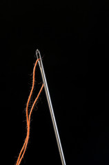 Needle and thread through on black background