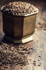Cumin.Caraway seeds on wooden table. Cumin in vintage bronze bowl and spoon.