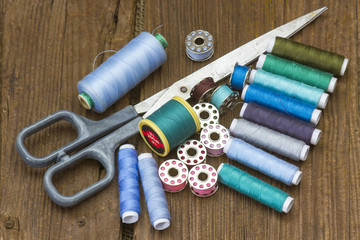 spools of thread and scissors on a wooden background