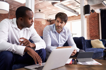 Businessmen Working On Sofas In Relaxation Area Of Office