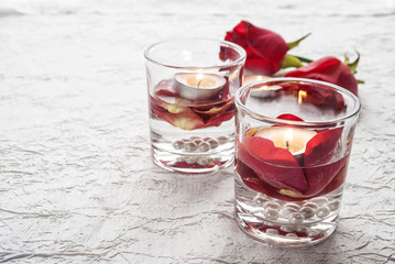St. Valentine's Day. A candle and red roses in glasses.