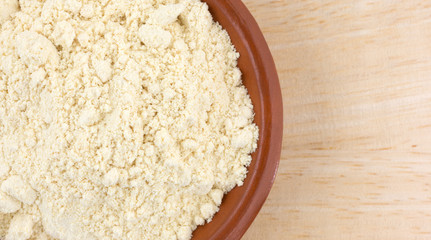 Soy powder in a small bowl on a wood table top close view.