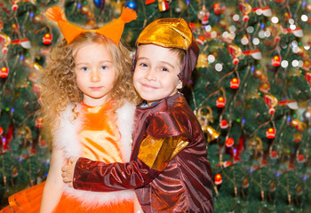 Portrait of child girl and boy in a suit squirrels around a Christmas tree decorated. Kids on holiday new year