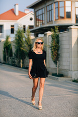 Fototapeta premium Portrait of beautiful blonde girl in black glasses and black dress. Hard light