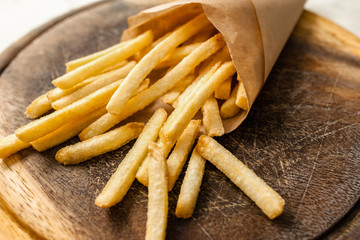 Portion of french fries on catering platter. Closeup of paper pack with traditional american fried potato. Junk fast food, restaurant menu, snack concept
