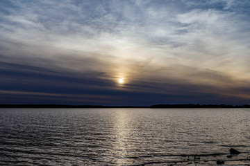 Cold late afternoon with sun behind clouds over a lake.