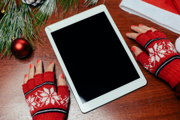 Woman's hand with red wool glove holding a tablet pc