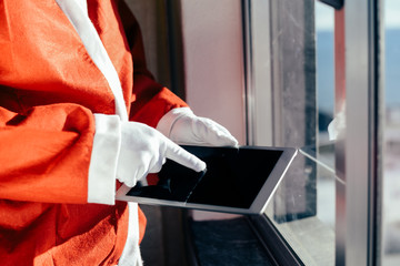 Santa Claus working at desk and using apps on a touch screen tablet