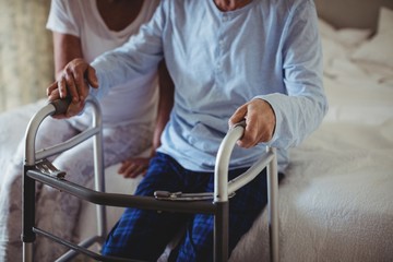 Senior woman helping senior man to walk with walker