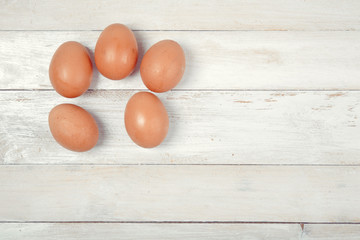 Raw chicken eggs on white wooden background