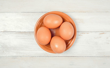 Raw chicken eggs on white wooden background