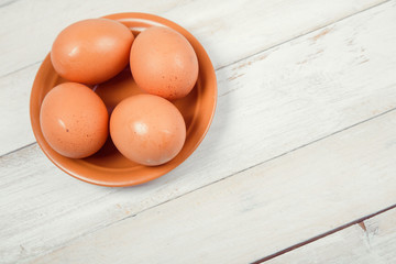 Raw chicken eggs on white wooden background