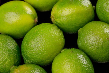 Fresh bunch of green Mexican limes on a black background.