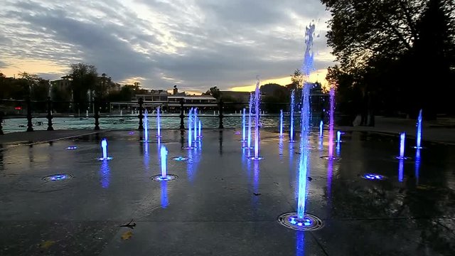 Colorfully lit fountain in a park at dusk