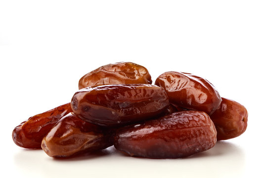 Close up of fresh brown dates against a white background 