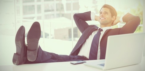 Successful businessman relaxing with his feet on his desk