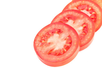 Closeup of red circular tomato slices layered and spread out on a white background