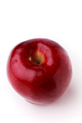 Overhead closeup of a ripe spotted apple with a stem on a white background