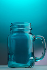 Mason jar beer glass with handle on a light blue background
