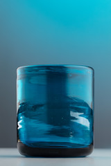 Isolated thick empty blue glass on a light blue and grey background
