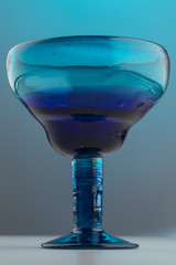 Blue short stem drinking glass on a moody light blue background