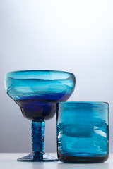 Two different blue glasses on a gradient background - one round, one rectangular