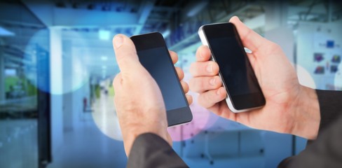 Composite image of businessman holding a phone in each hand 3d