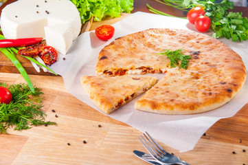 Selective Focus vegetable closed pies with cheese and sun-dried tomatoes on the table. Composition of ingridients.