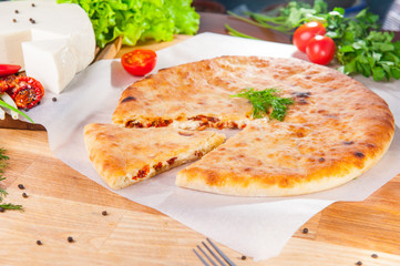 Selective Focus vegetable closed pies with cheese and sun-dried tomatoes on the table. Composition of ingridients.