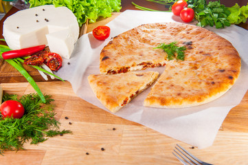 Selective Focus vegetable closed pies with cheese and sun-dried tomatoes on the table. Composition of ingridients.