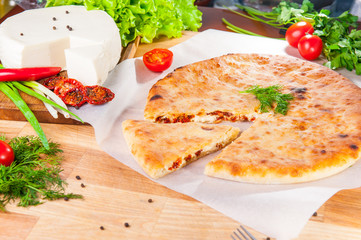 Selective Focus vegetable closed pies with cheese and sun-dried tomatoes on the table. Composition of ingridients.