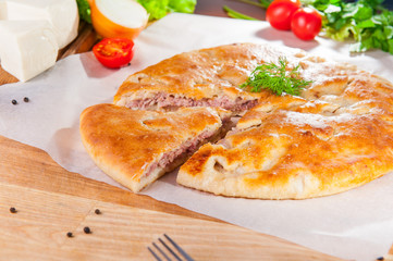Selective Focus Traditional meat closed pie on the table. Composition of ingridients.