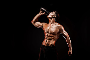 Muscular man with protein drink in shaker over dark background