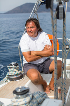 Mature man sits on his sail yacht. Vacation, sailing, travel.
